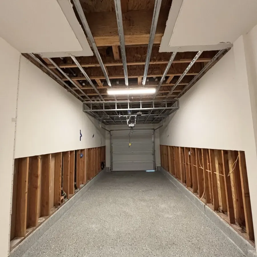 Garage with drywall flood cuts along both walls after a water heater leak in Mission Viejo