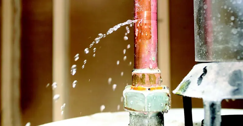 Water spraying from a split copper supply pipe at a fitting